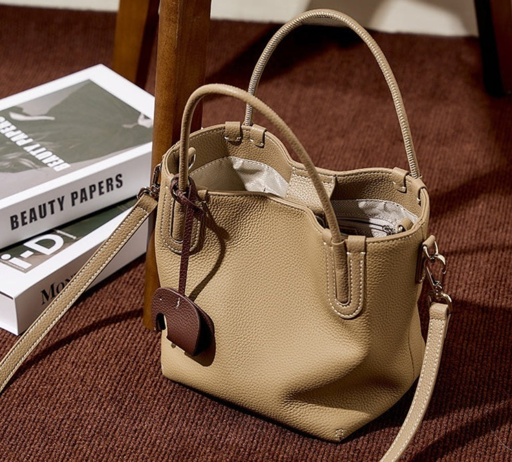 Beige handbag on a brown surface with books in the background