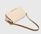 Beige woven handbag with a brown strap on a light gray background