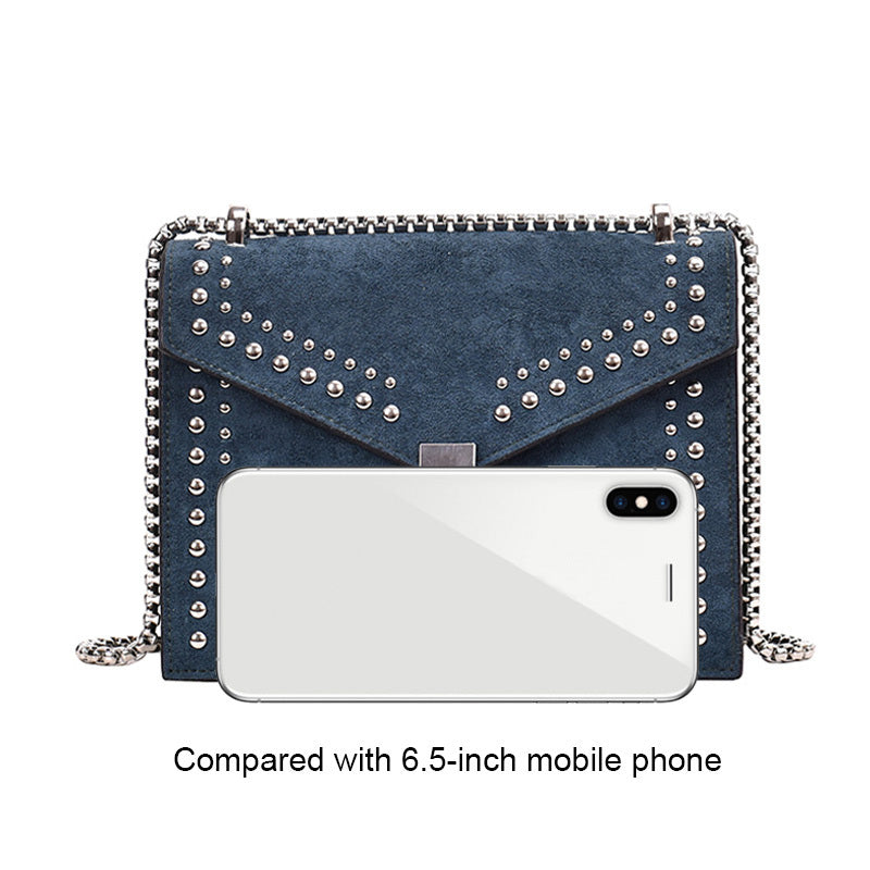 Blue studded handbag next to a 6.5-inch mobile phone on a white background