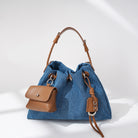 Blue denim handbag with brown leather accents on a white background