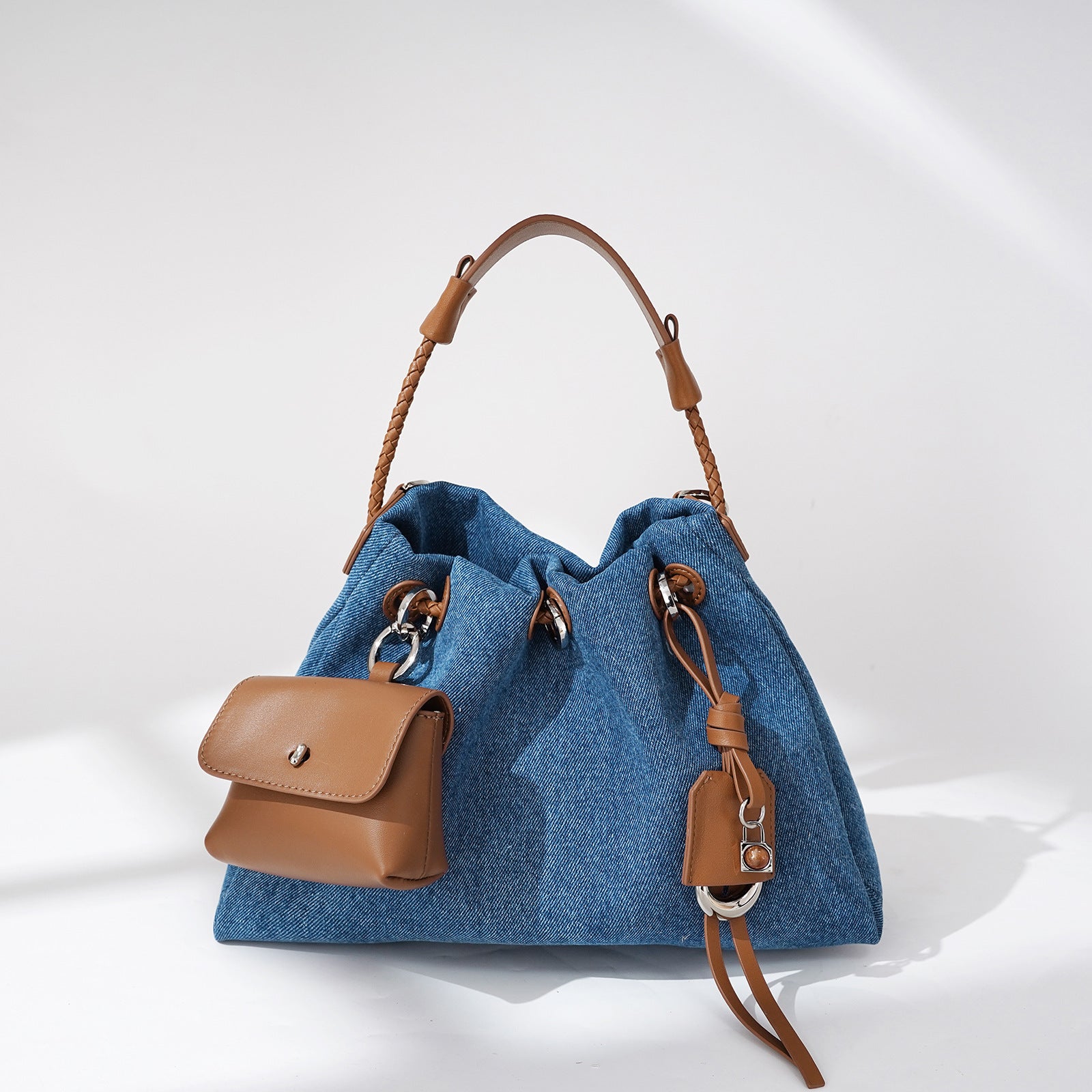 Blue denim handbag with brown leather accents on a white background