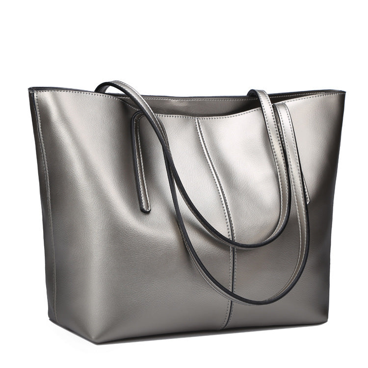 Silver tote bag with black handles on a white background