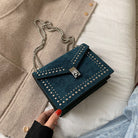 Blue studded handbag held by a hand with red nail polish, against a neutral background.