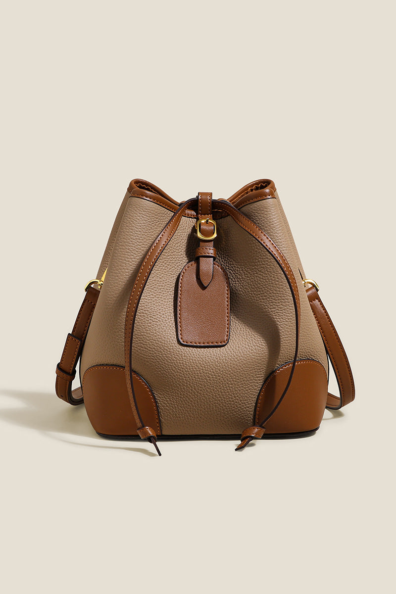 Two-tone beige and brown handbag on a light beige background
