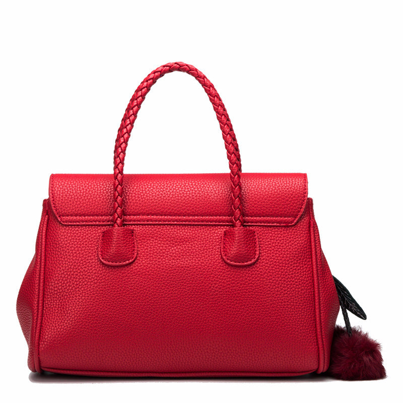 Red handbag with braided handle on a white background