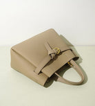 Beige handbag on a light beige background with text about the bag's features.