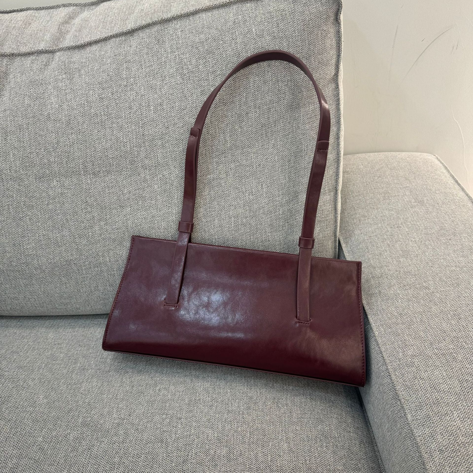 Brown leather handbag on a gray sofa