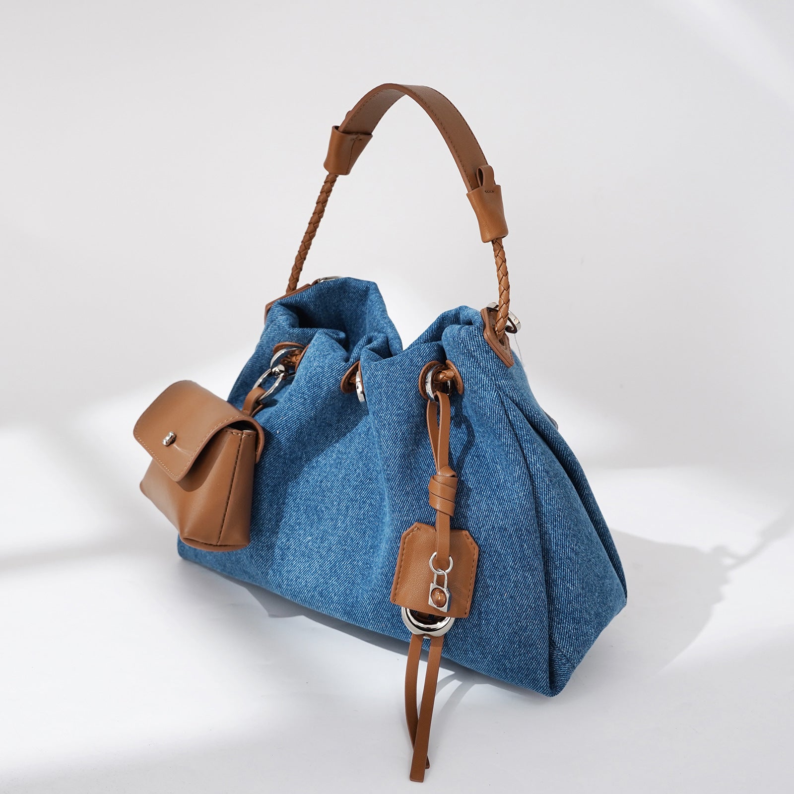 Blue Denim handbag with brown leather accents on a white background