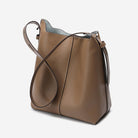 Brown leather handbag with a shoulder strap on a light gray background