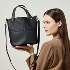 Woman holding a black handbag with a plain background