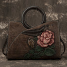 Brown leather handbag with floral design on a textured brown background