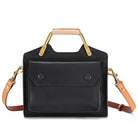 Black handbag with gold hardware and tan strap on a white background
