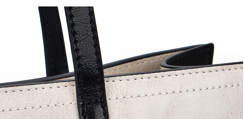 Close-up of a beige handbag with black handles on a white background
