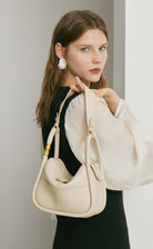 Woman holding a beige handbag against a neutral background