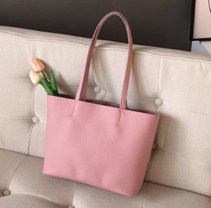 Pink handbag on a beige sofa with a minimalistic wall art in the background