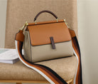Two-tone handbag with a strap draped over a chair against a neutral background
