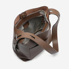Brown leather handbag with a shoulder strap on a light gray background