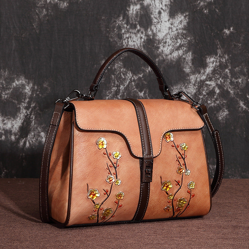 Brown handbag with floral embroidery on a textured dark background
