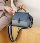 Blue handbag with a striped strap on a wooden surface