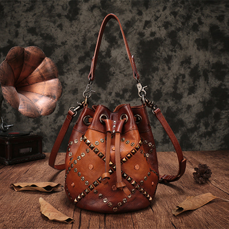 Brown leather bag with studs on a wooden surface with a vintage gramophone in the background.