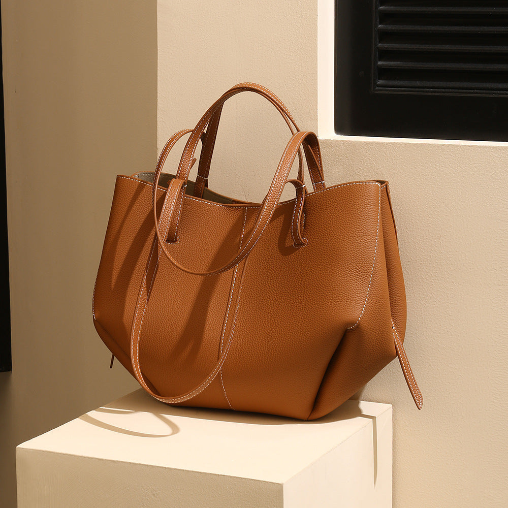 Brown leather handbag on a white surface with a neutral background
