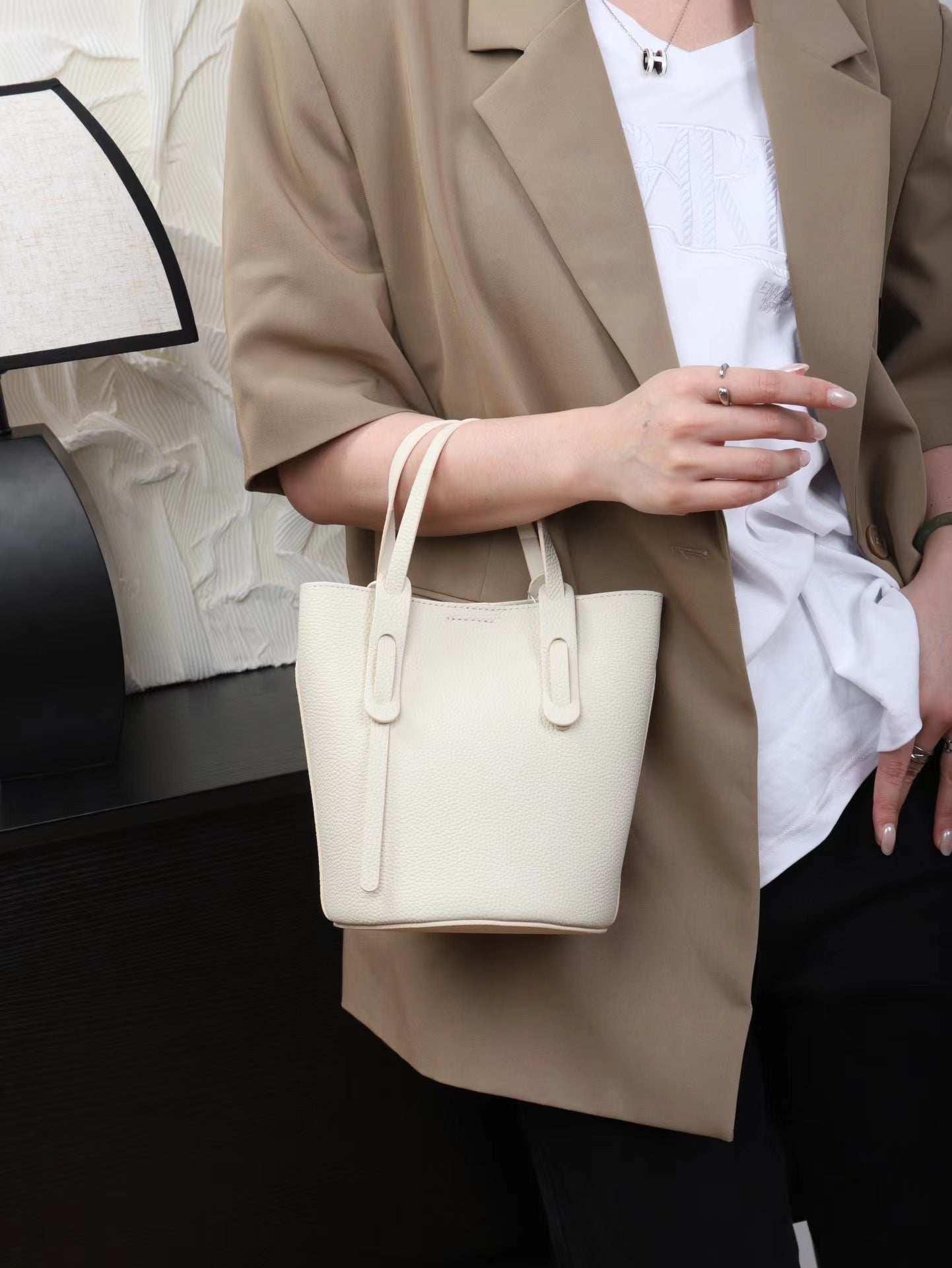 Person holding a white handbag with a neutral background