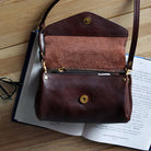 Brown leather handbag with gold accents on an open book