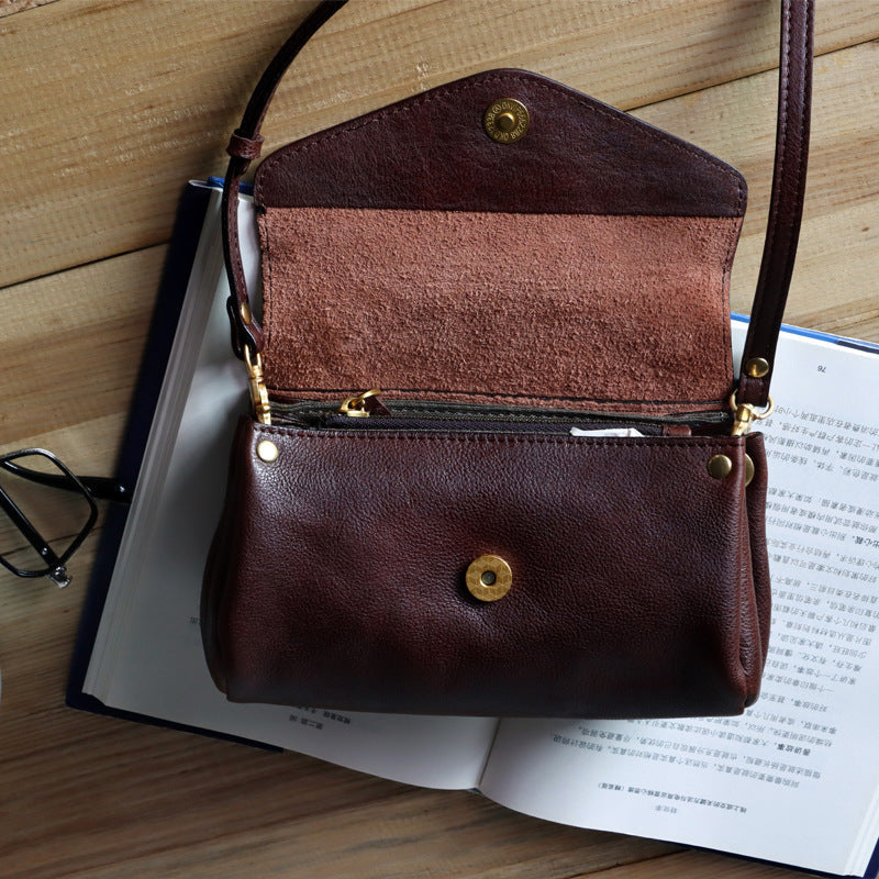 Brown leather handbag with gold accents on an open book