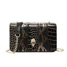 Black and gold patterned handbag with a chain strap on a white background