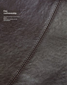 Close-up of a dark brown leather surface with stitching details, emphasizing fine craftsmanship.