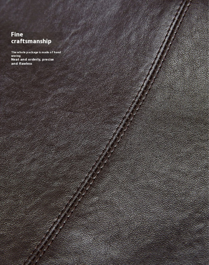 Close-up of a dark brown leather surface with stitching details, emphasizing fine craftsmanship.