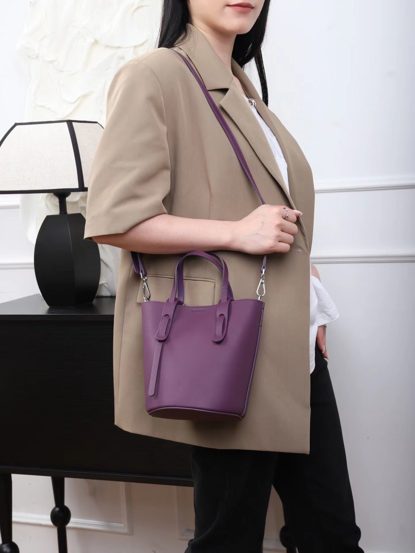 Person holding a purple handbag in a neutral setting