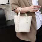 Person holding a white handbag with a neutral background