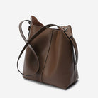Brown leather handbag with a shoulder strap on a light gray background