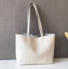 White tote bag on a white surface with a gray background