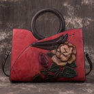 Red leather handbag with floral embossing on a textured gray background