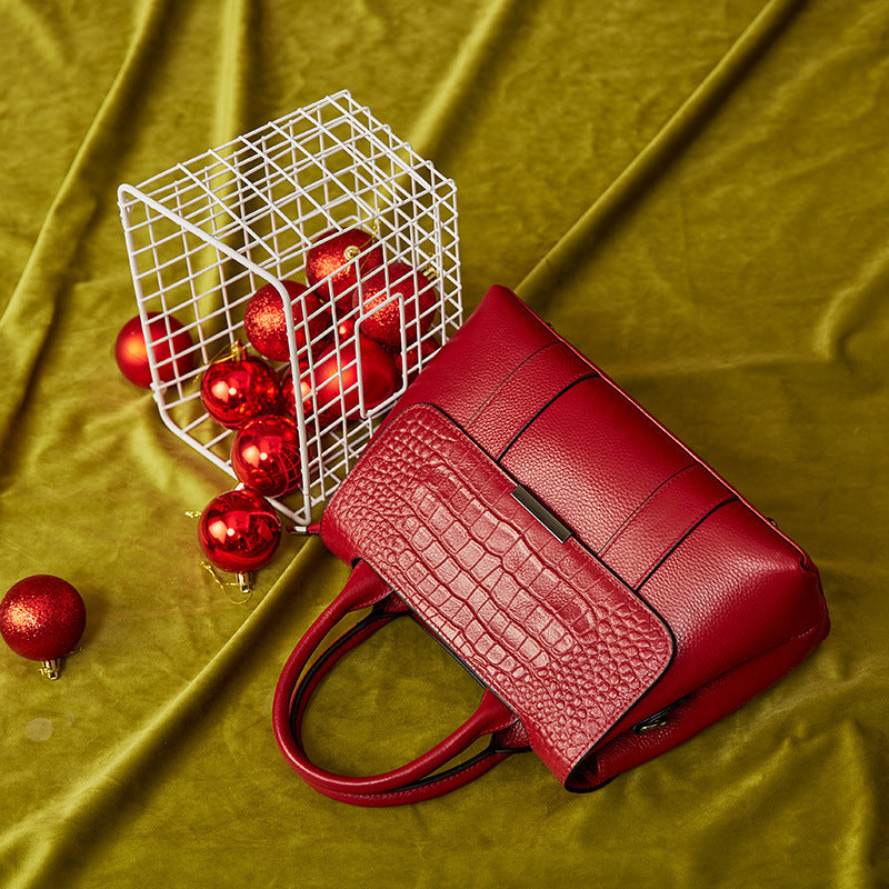 Red textured handbag with Christmas ornaments on a green fabric background