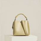 Beige handbag on a white pedestal against a light beige background