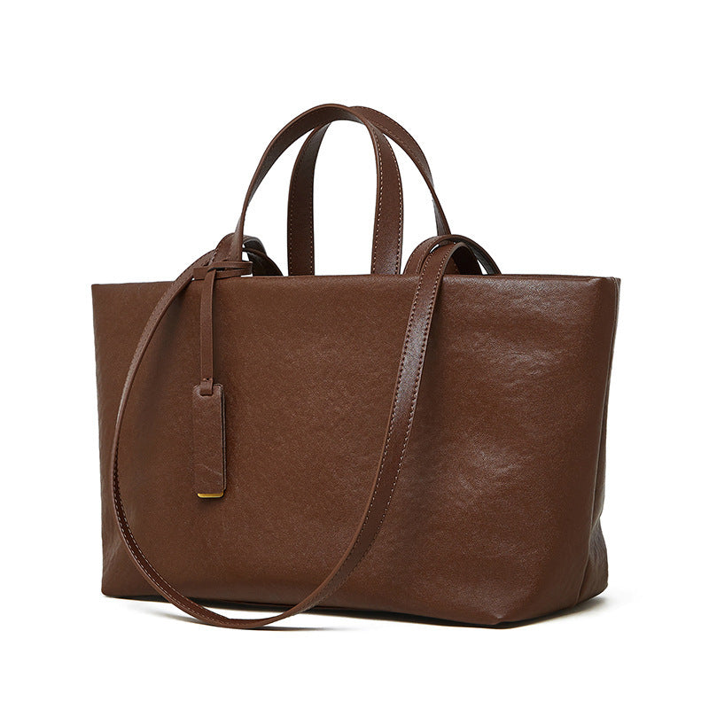 Brown leather tote bag with a shoulder strap on a white background