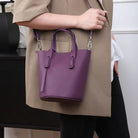 Person holding a purple handbag with a neutral background