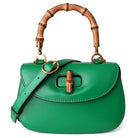 Green handbag with a wooden handle on a white background
