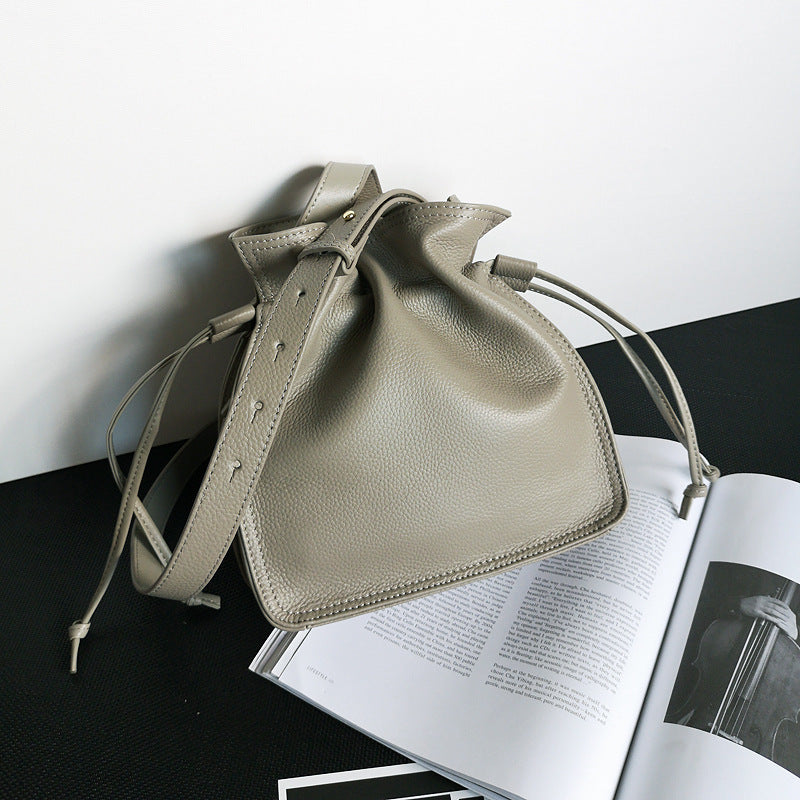 Beige leather drawstring bag on an open magazine with a white background