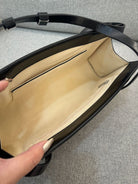 Black handbag with beige interior on a gray background