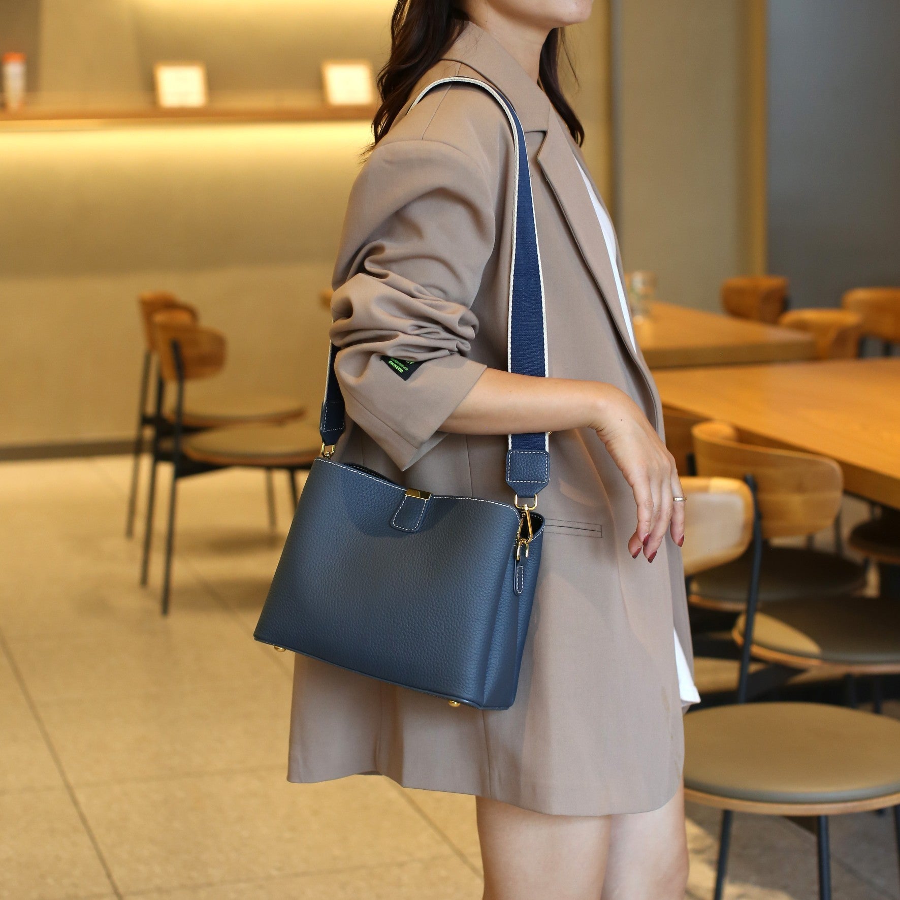 Woman holding a blue handbag in an indoor setting