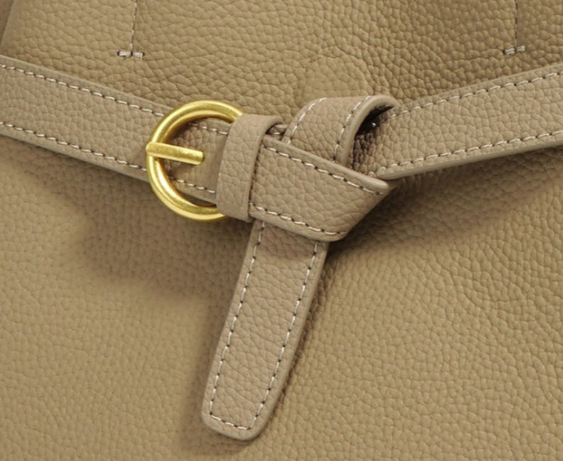 Brown leather bag with gold buckle on a light gray background