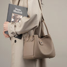 Person holding a beige handbag and a book titled 'Duste Blackish' against a neutral background
