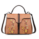 Brown handbag with floral embroidery on a white background