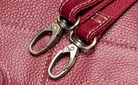 Close-up of a red leather strap with metal clasps on a textured red surface