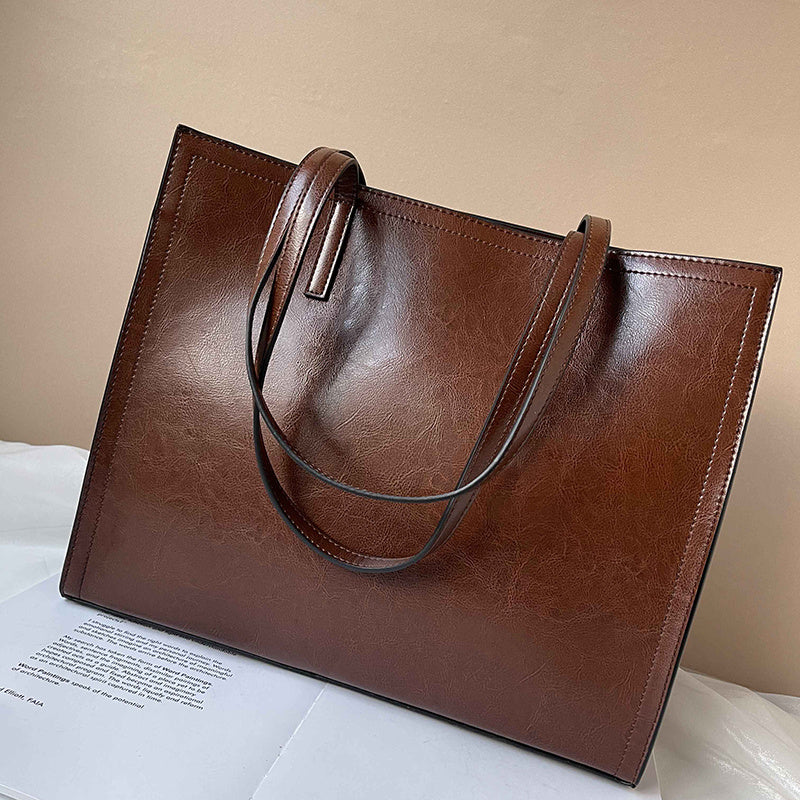 Brown leather tote bag on a light surface with a neutral background