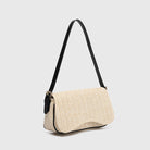 Beige woven handbag with black strap on a light gray background